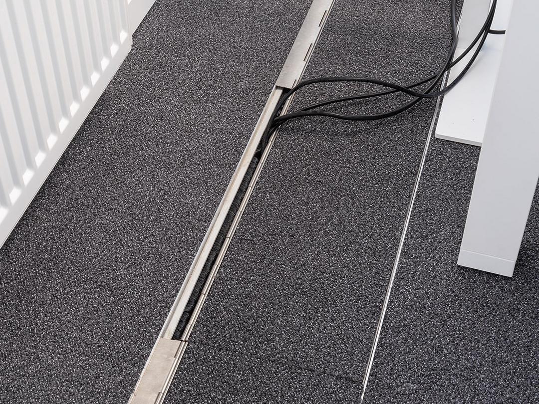 Das in den Boden eingelassene Kanalsystem für Kabel, geschlossen, in einem Büro.