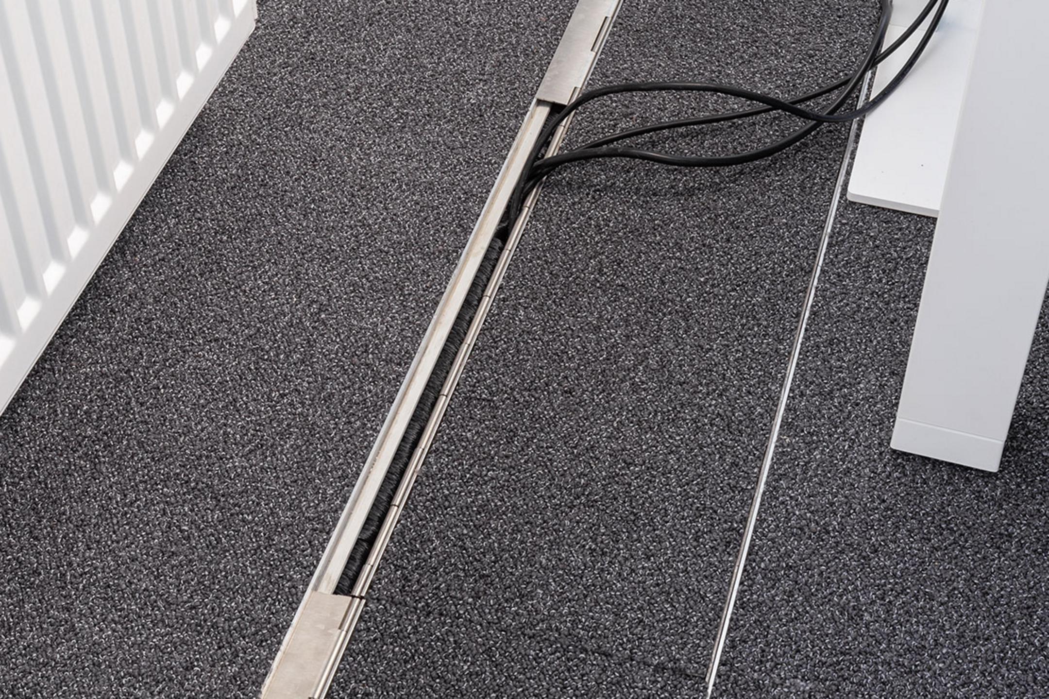 Das in den Boden eingelassene Kanalsystem für Kabel, geschlossen, in einem Büro.