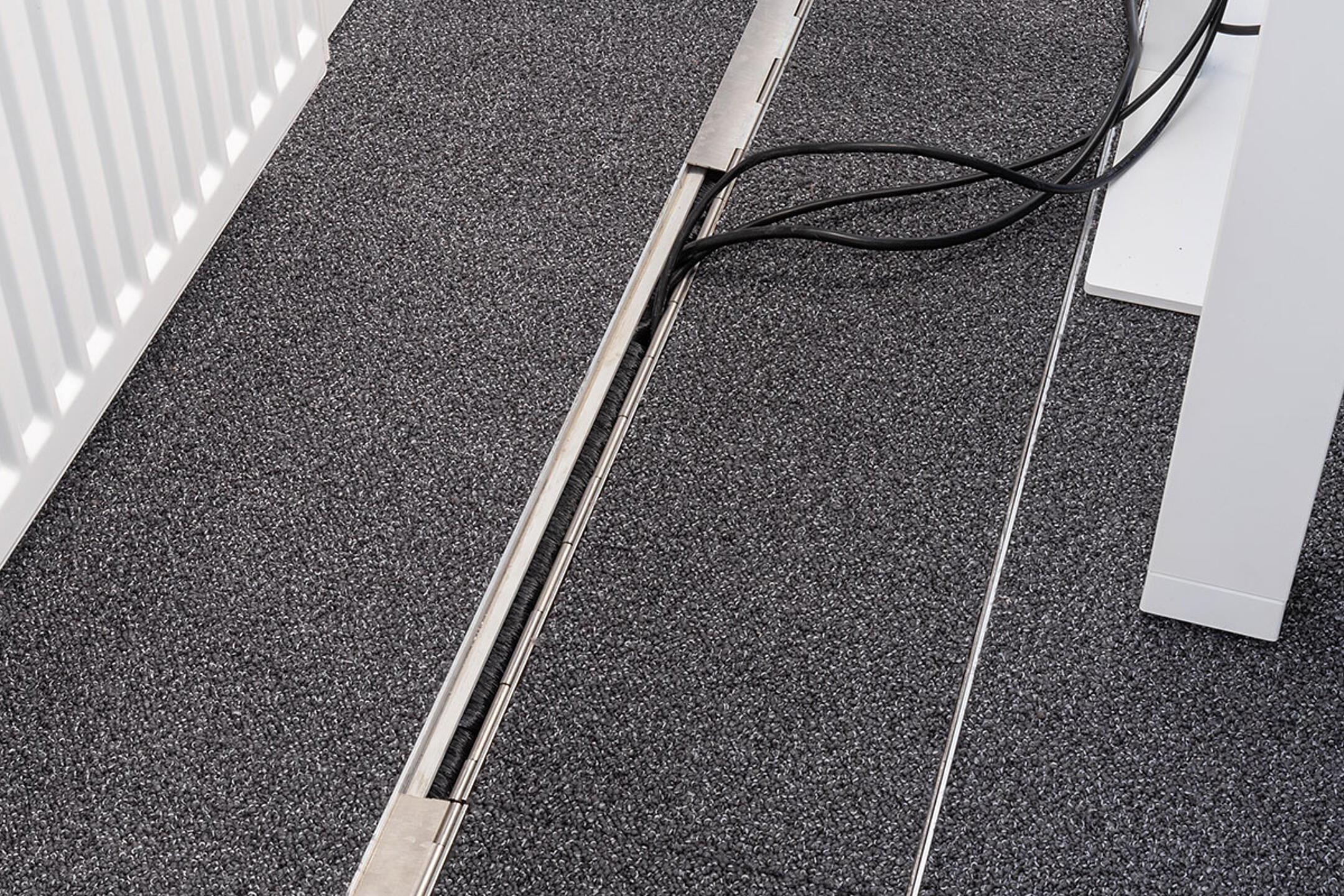 Das in den Boden eingelassene Kanalsystem für Kabel, geschlossen, in einem Büro.