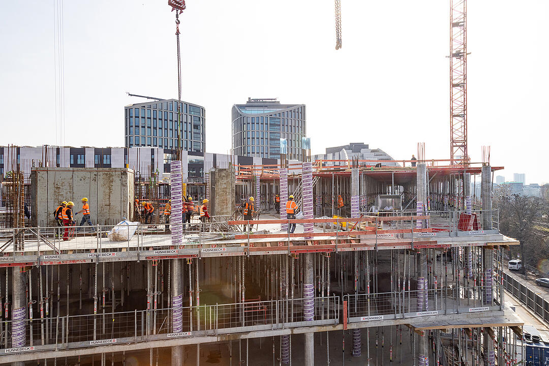 Mehrstöckiges Gebäude im Rohbau mit Arbeitern und Kränen