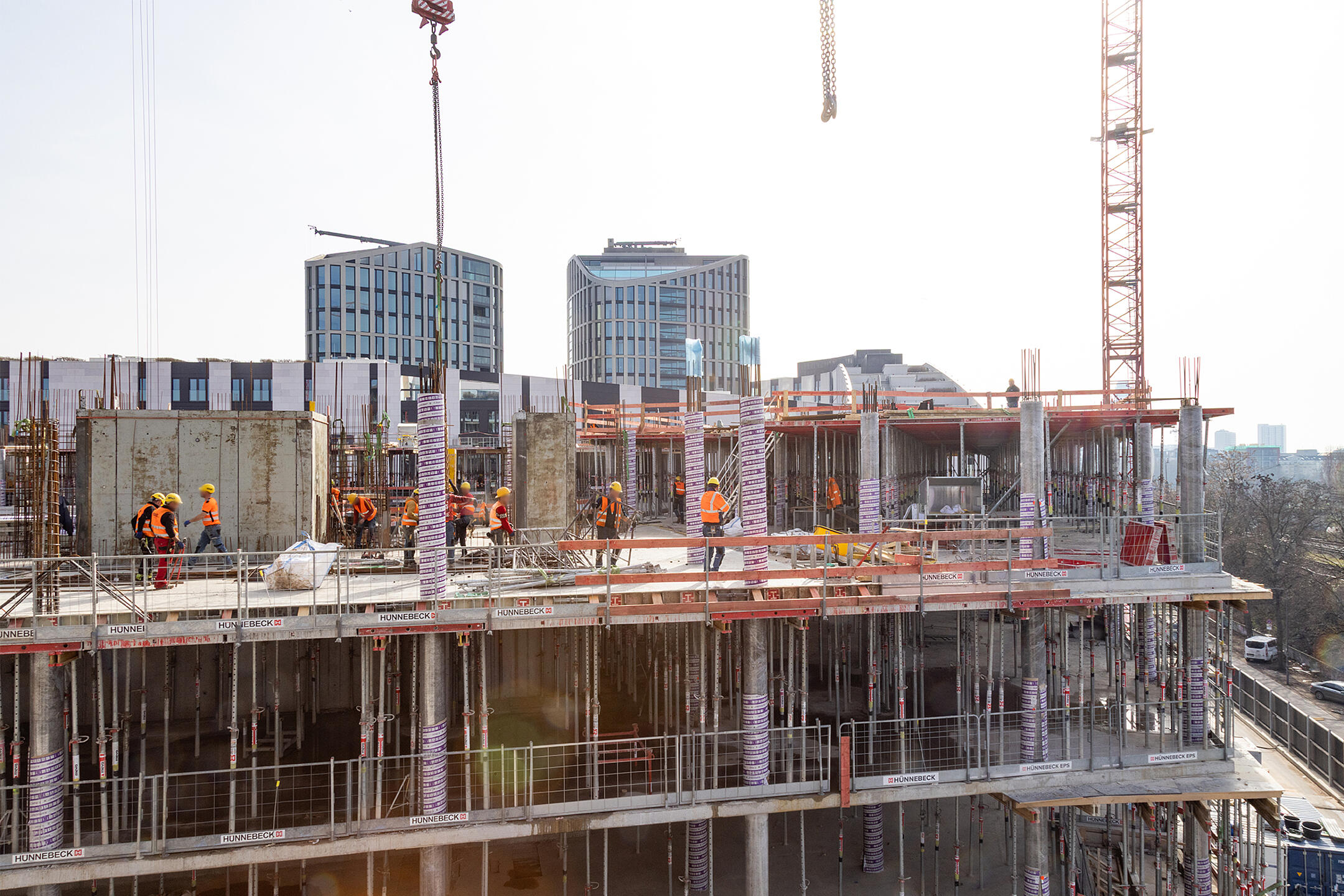 Mehrstöckiges Gebäude im Rohbau mit Arbeitern und Kränen