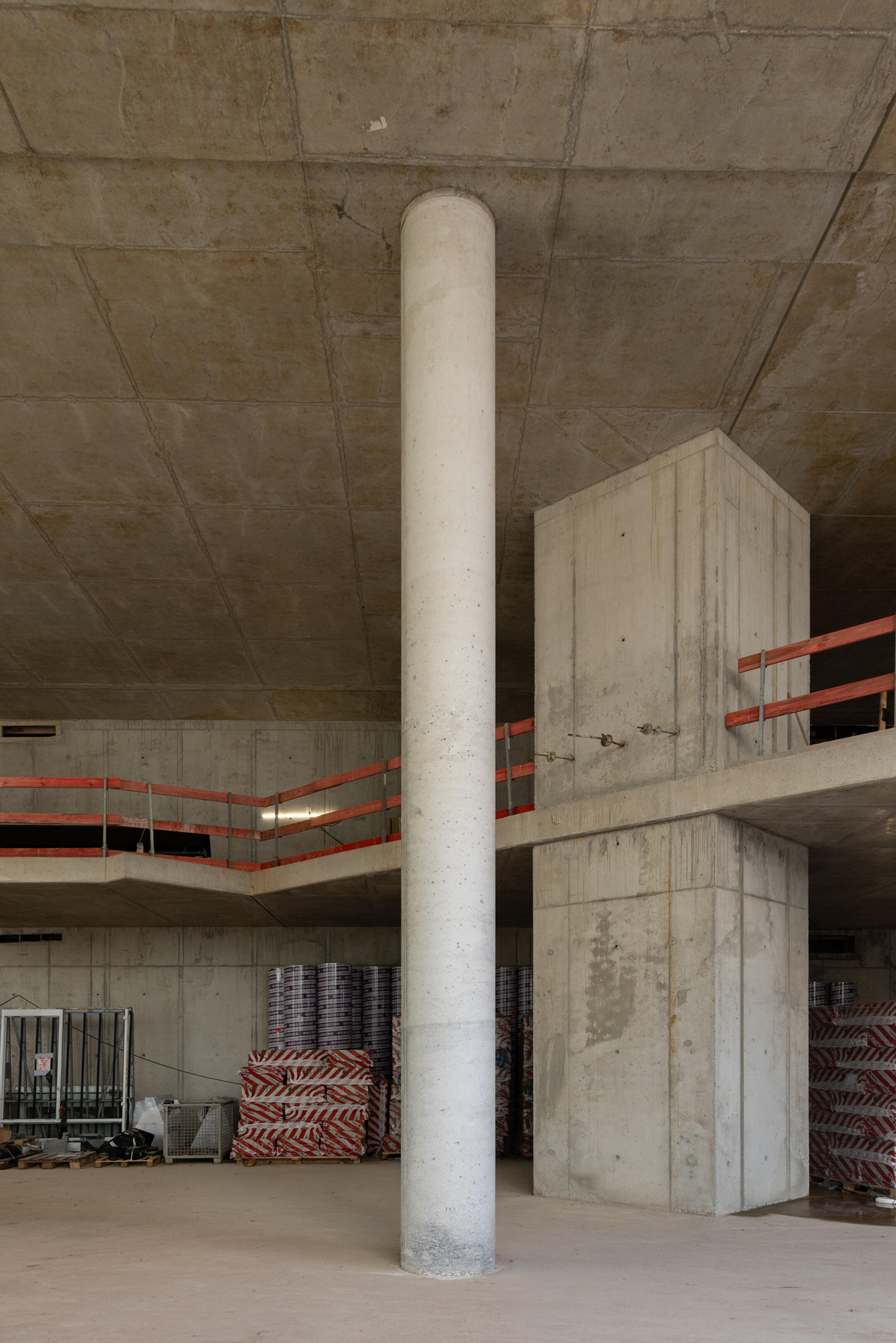 Betonstütze in einem Rohbaukomplex, im Hintergrund steht weiteres Baumaterial