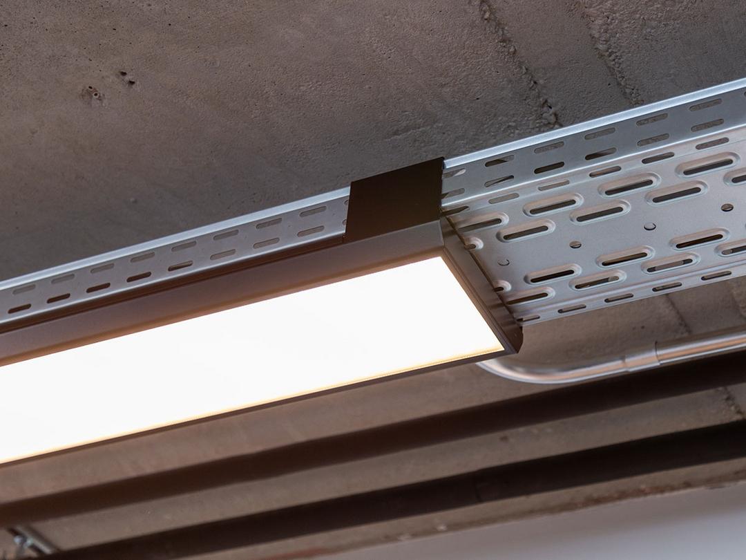 Eine von der Decke hängende, nicht lackierte Kabelrinne für Deckenlampen.