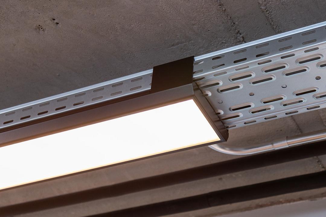 Eine von der Decke hängende, nicht lackierte Kabelrinne für Deckenlampen.