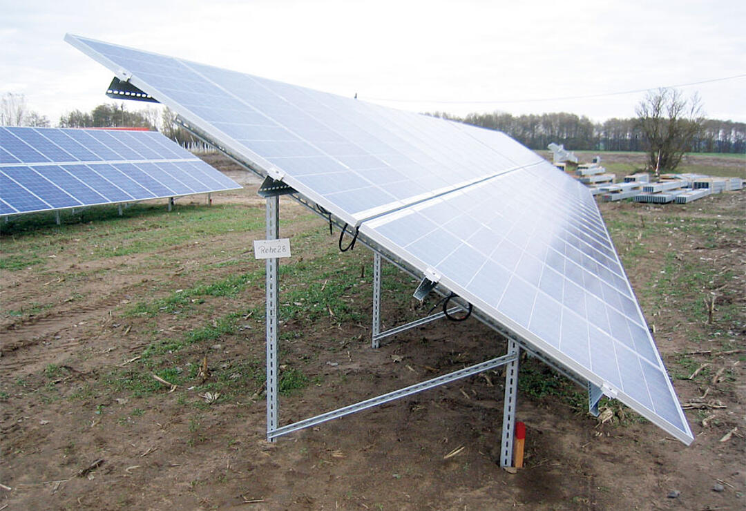 Freiland-Solaranlage mit geneigten Modulen auf verzinktem Stahlgestell; Schild „Reihe 28“ an einem Pfosten befestigt.