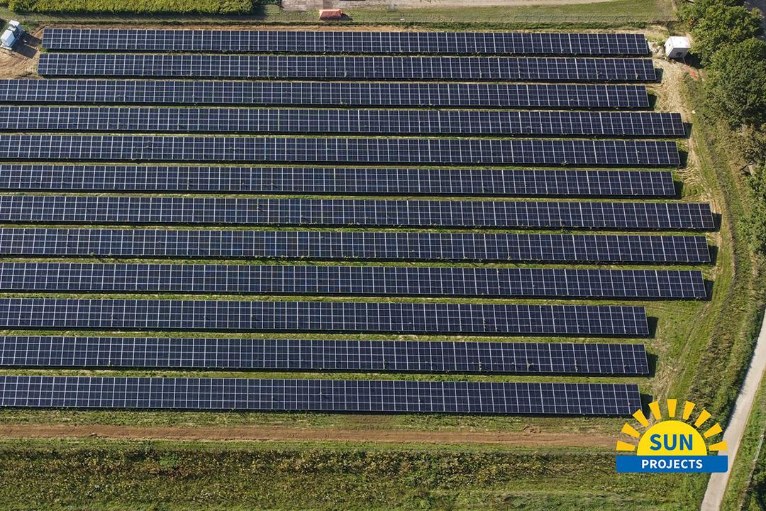 Luftaufnahme einer landwirtschaftlichen Fläche mit Solarpanelen und Gewächshäusern im Anschnitt