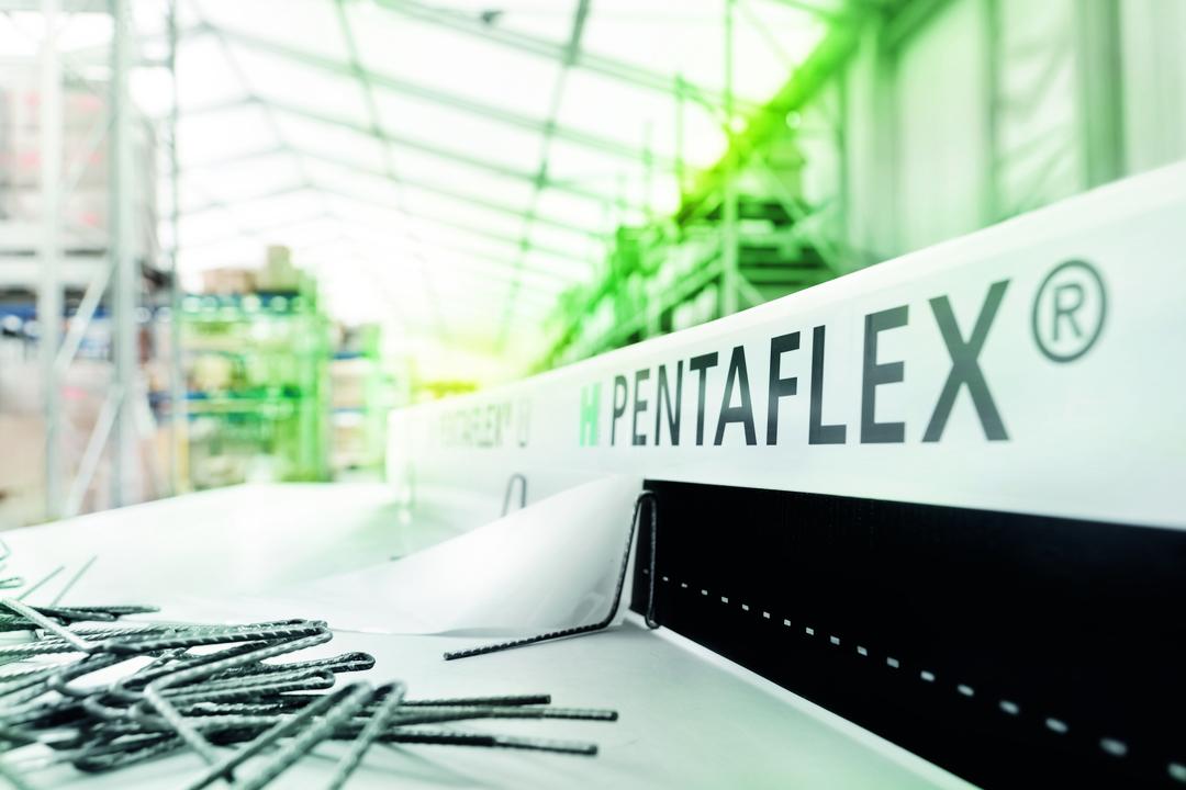 Blick in eine lichtdurchflutete Lagerhalle. Im Vordergrund steht die Abdichtungslösung PENTAFLEX auf einem Arbeitstisch.