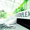 Blick in eine lichtdurchflutete Lagerhalle. Im Vordergrund steht die Abdichtungslösung PENTAFLEX auf einem Arbeitstisch.