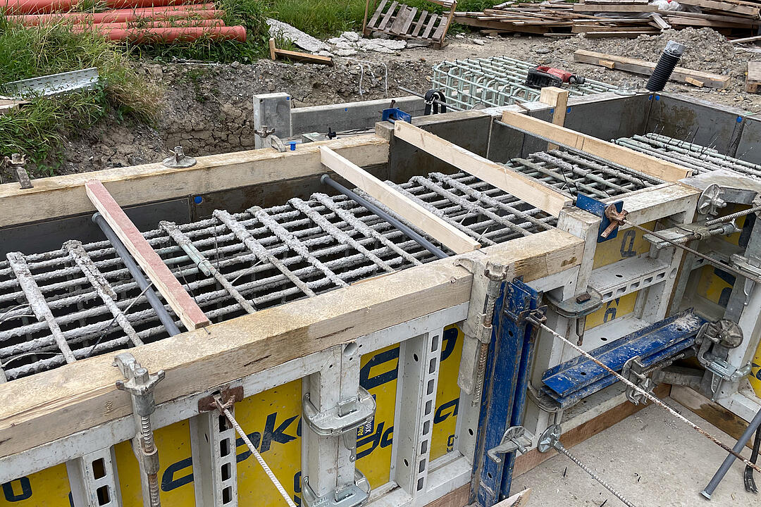 GFK-Bewehrung in Holz-Metall-Verkleidung, im Hintergrund sind Paletten und Rohre zu sehen.