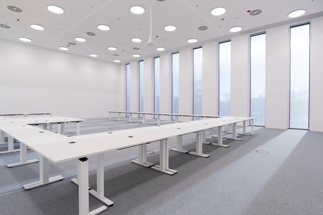Büroraum mit weißen Tischen und Fensterfront