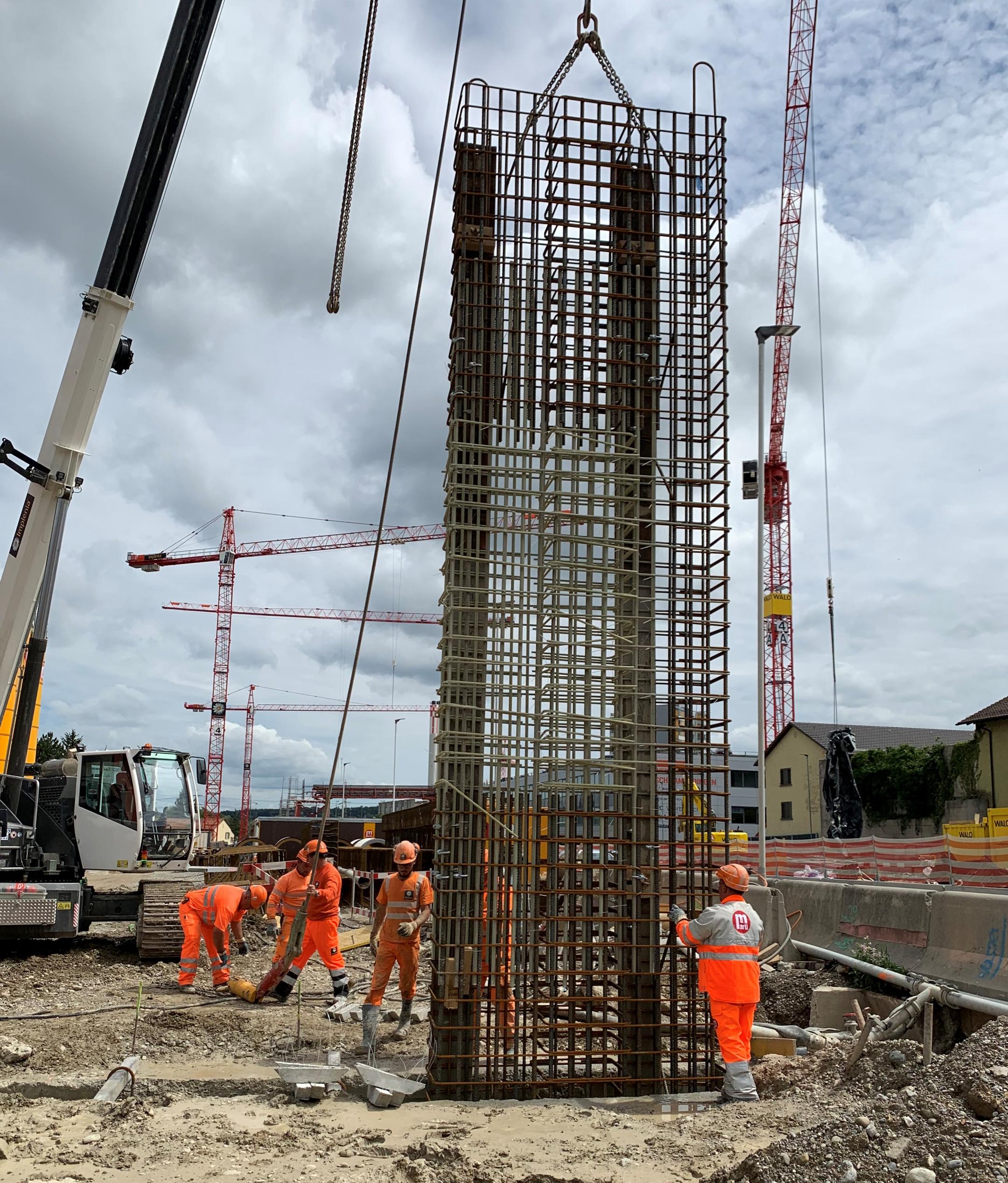 Bauarbeiter arbeiten auf einer Baustelle an der Einhausung einer Straße.