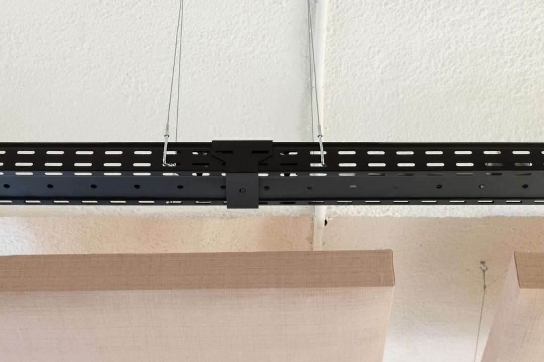 Detailansicht einer schwarzen Kabelrinne mit Verbinder, im Hintergrund sind Akustikelemente erkennbar.