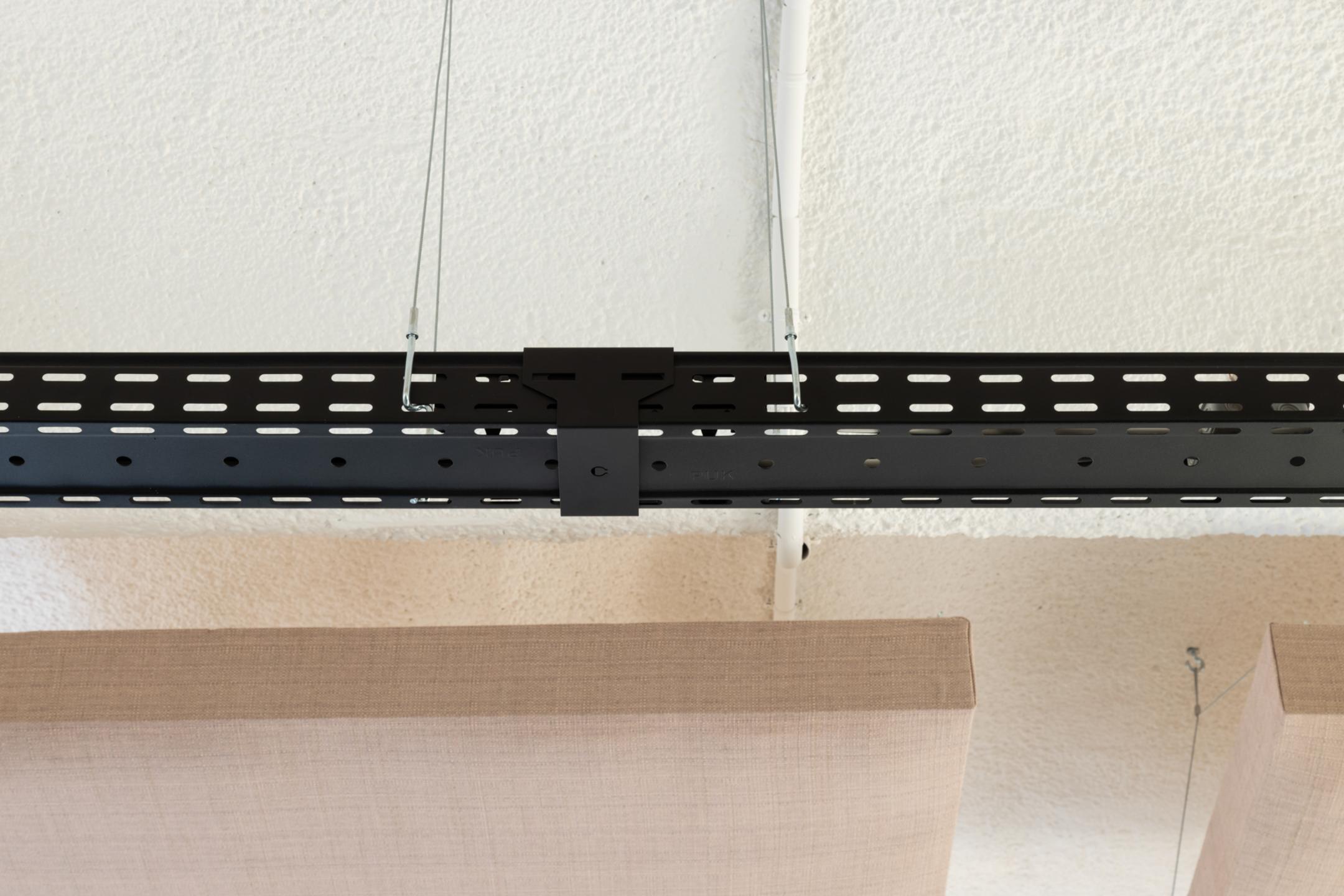 Detailansicht einer schwarzen Kabelrinne mit Verbinder, im Hintergrund sind Akustikelemente erkennbar.