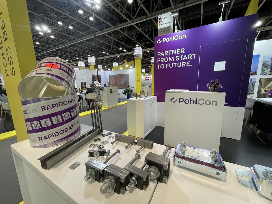 Messestand mit verschiedenen Ausstellungsstücken, unter anderem Schalrohr, Ankerschienen und Aufzugisolierung