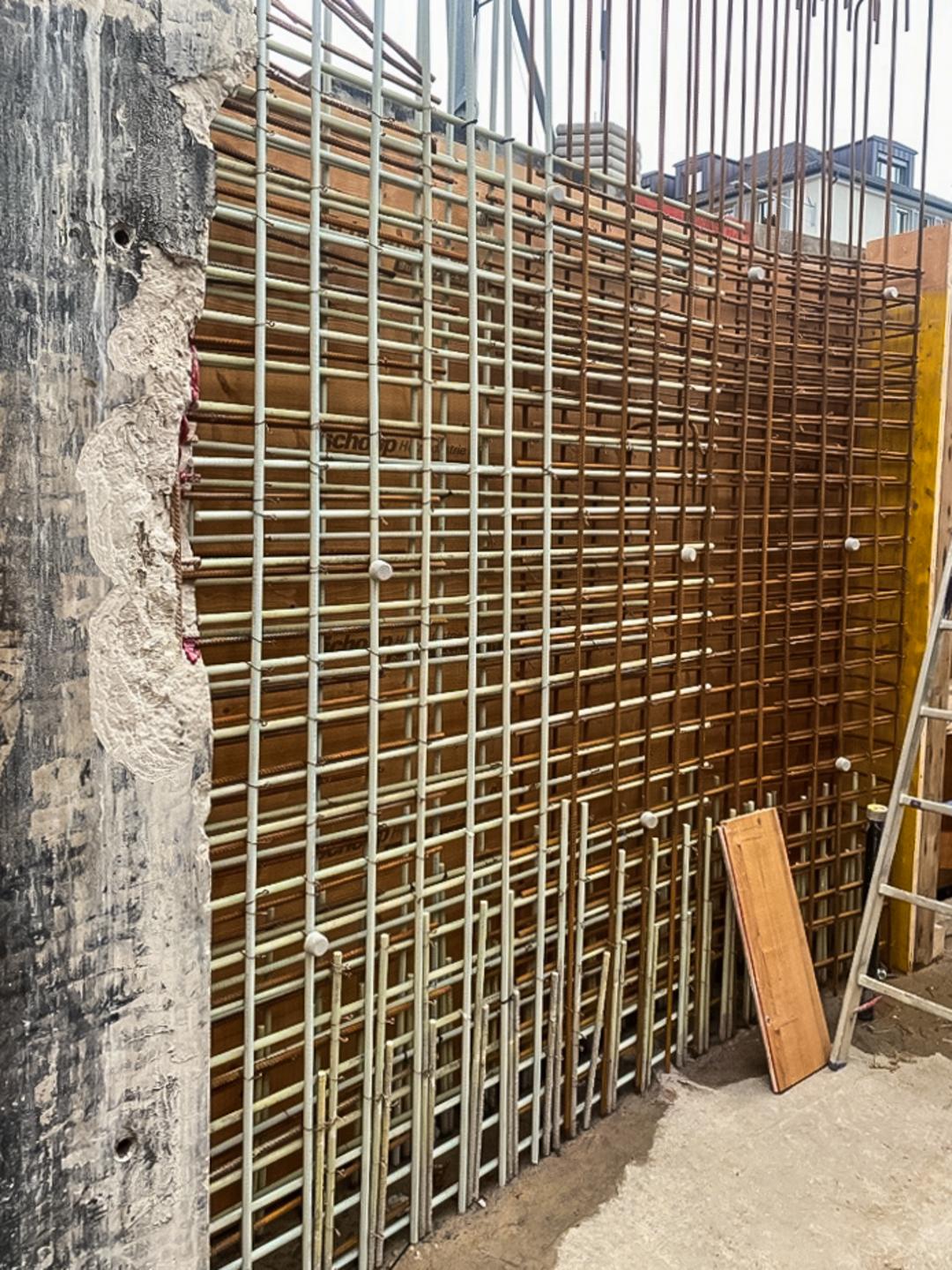 Bewehrung einer Betonwand mit vertikalen und horizontalen Glasfaserkunststoffbewehrungsstäben vor Schalung auf einer Baustelle