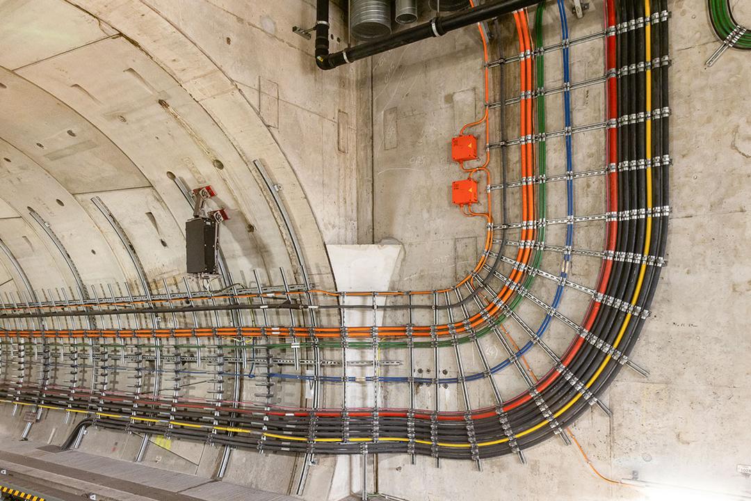 Präzise verlegte farbcodierte Kabel in einem Tunnel, geführt in Halterungen entlang der Wand