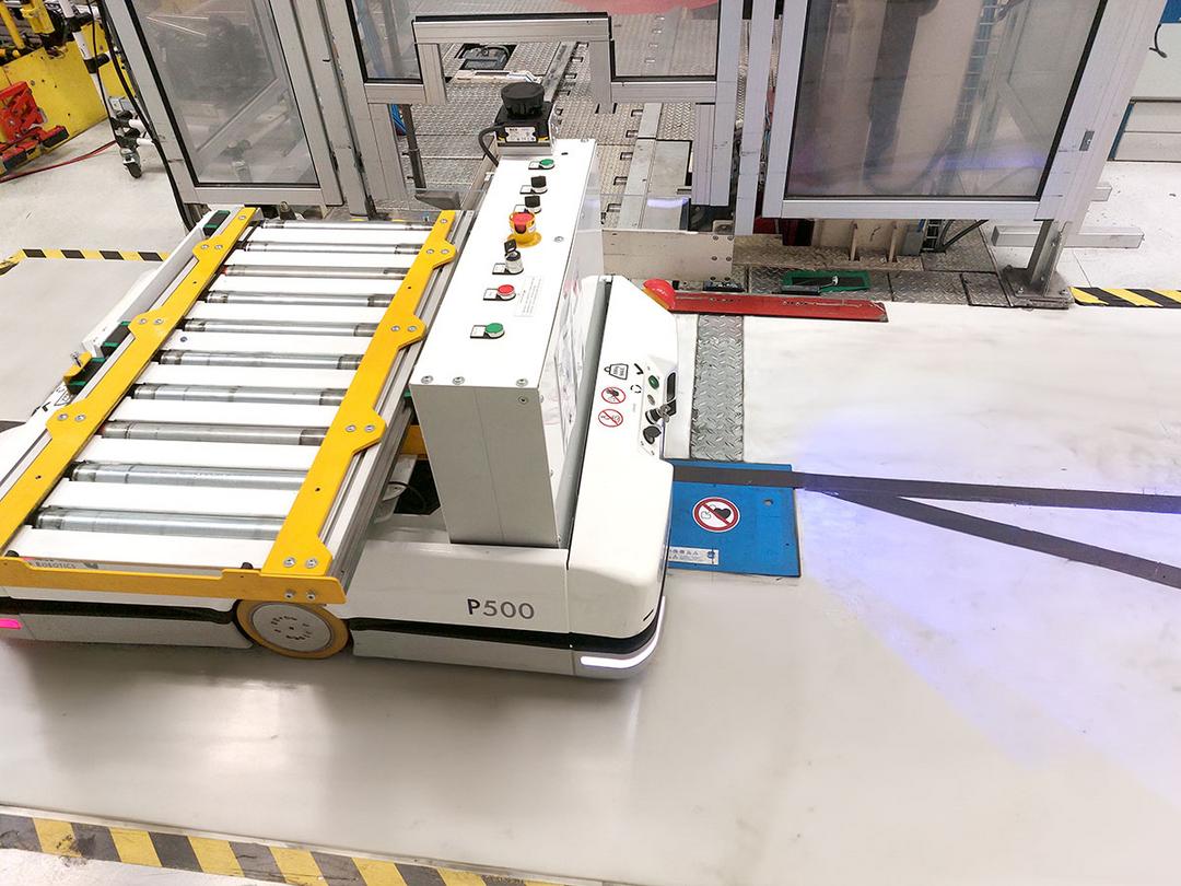 Automatisierter Transportroboter steht auf einer blauen induktiven Ladeeinbaueinheit