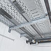 Industrieinstallation mit Kabeltrassen und Rohrleitungen an Decke und Wand in einem Technikraum mit Sichtbeton