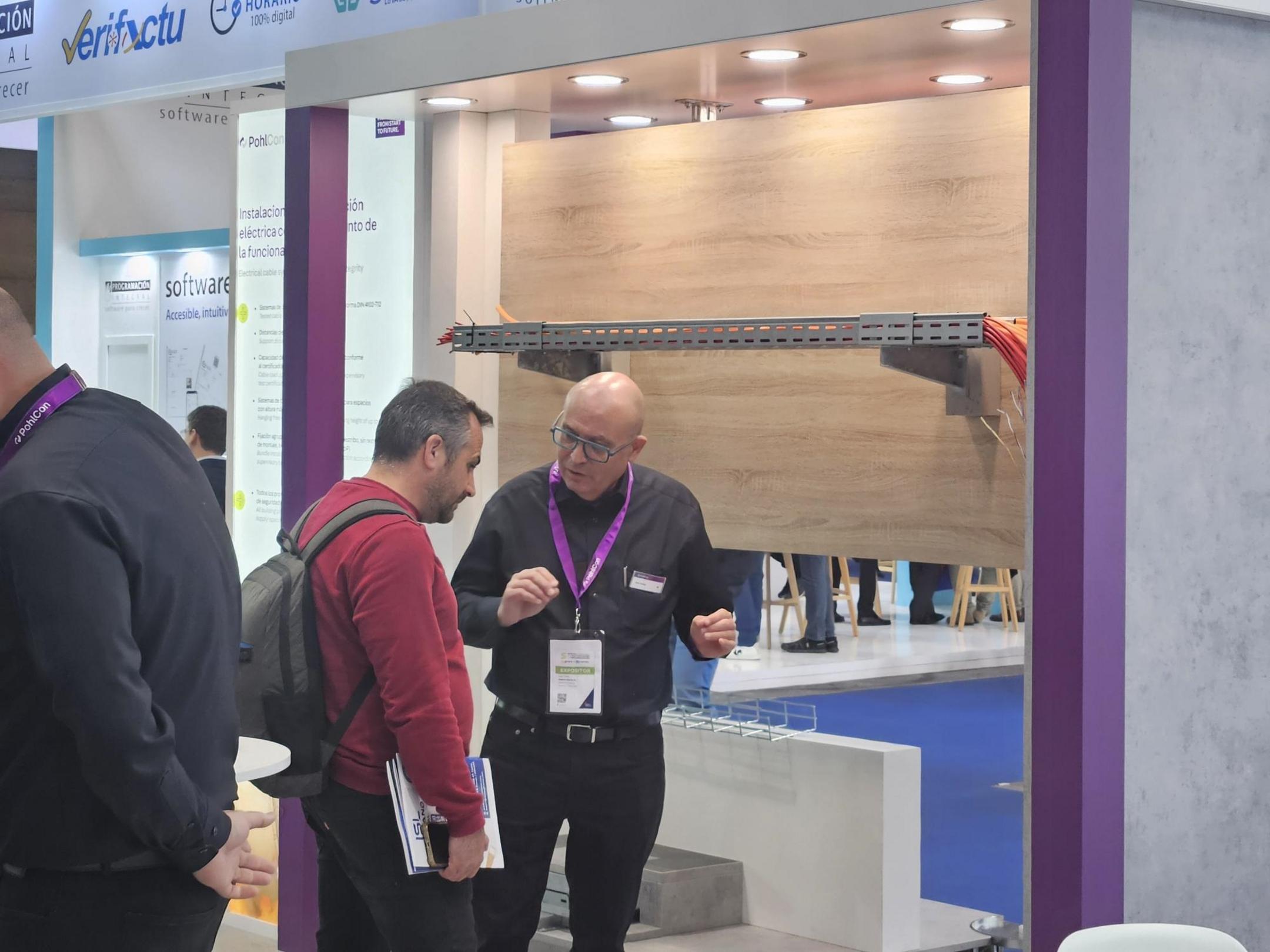 Messestand mit Ausstellungsstück Kabeltragsystem, Messepersonal und Besuchern