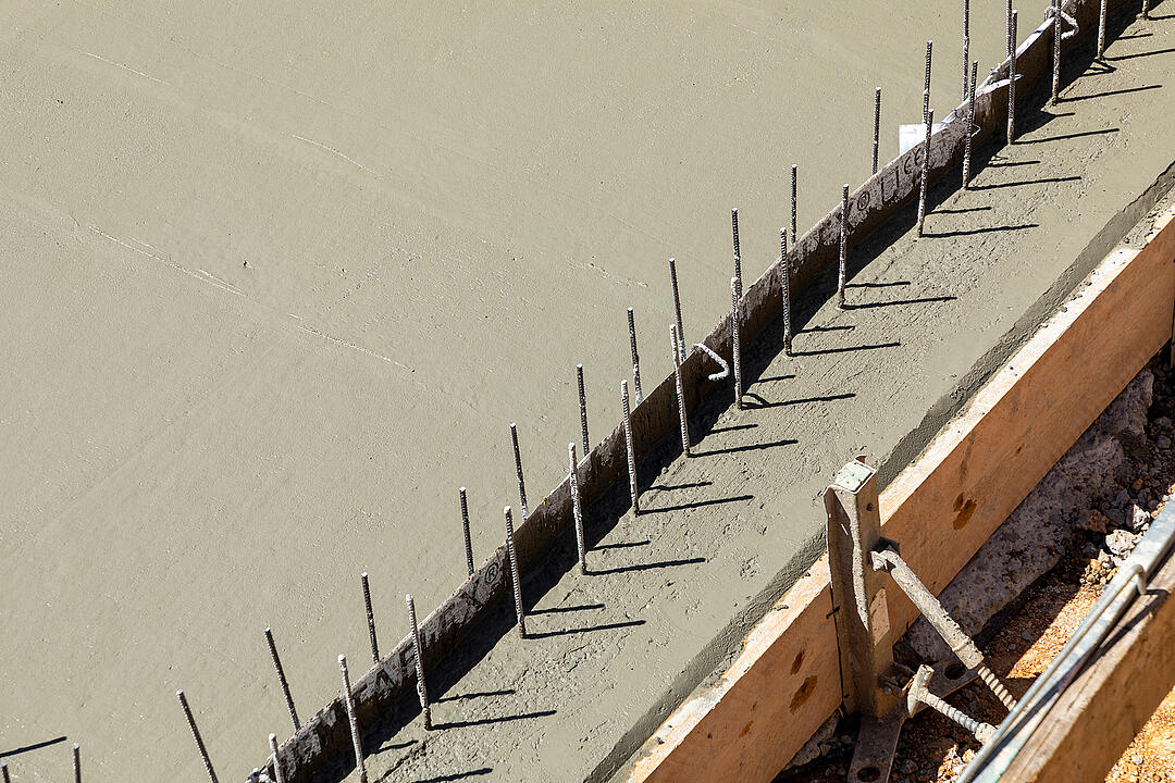 A freshly concreted floor slab with a construction joint, protruding reinforcement and formwork at the edge.