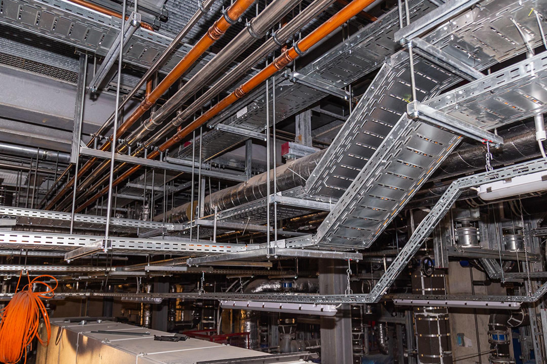 Technikraum-Decke mit Rohren, Kabeltrassen und Lüftungsrohren in einem Industrie- oder Maschinenraum
