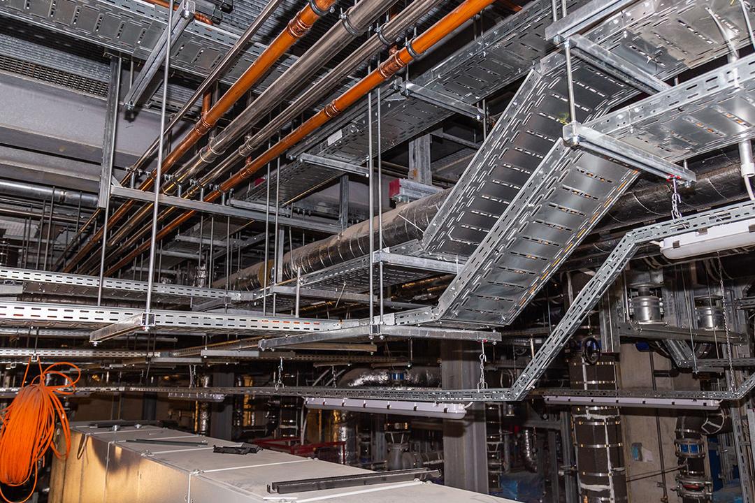 Technikraum-Decke mit Rohren, Kabeltrassen und Lüftungsrohren in einem Industrie- oder Maschinenraum