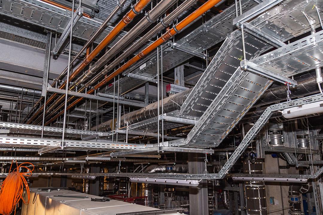 Technikraum-Decke mit Rohren, Kabeltrassen und Lüftungsrohren in einem Industrie- oder Maschinenraum