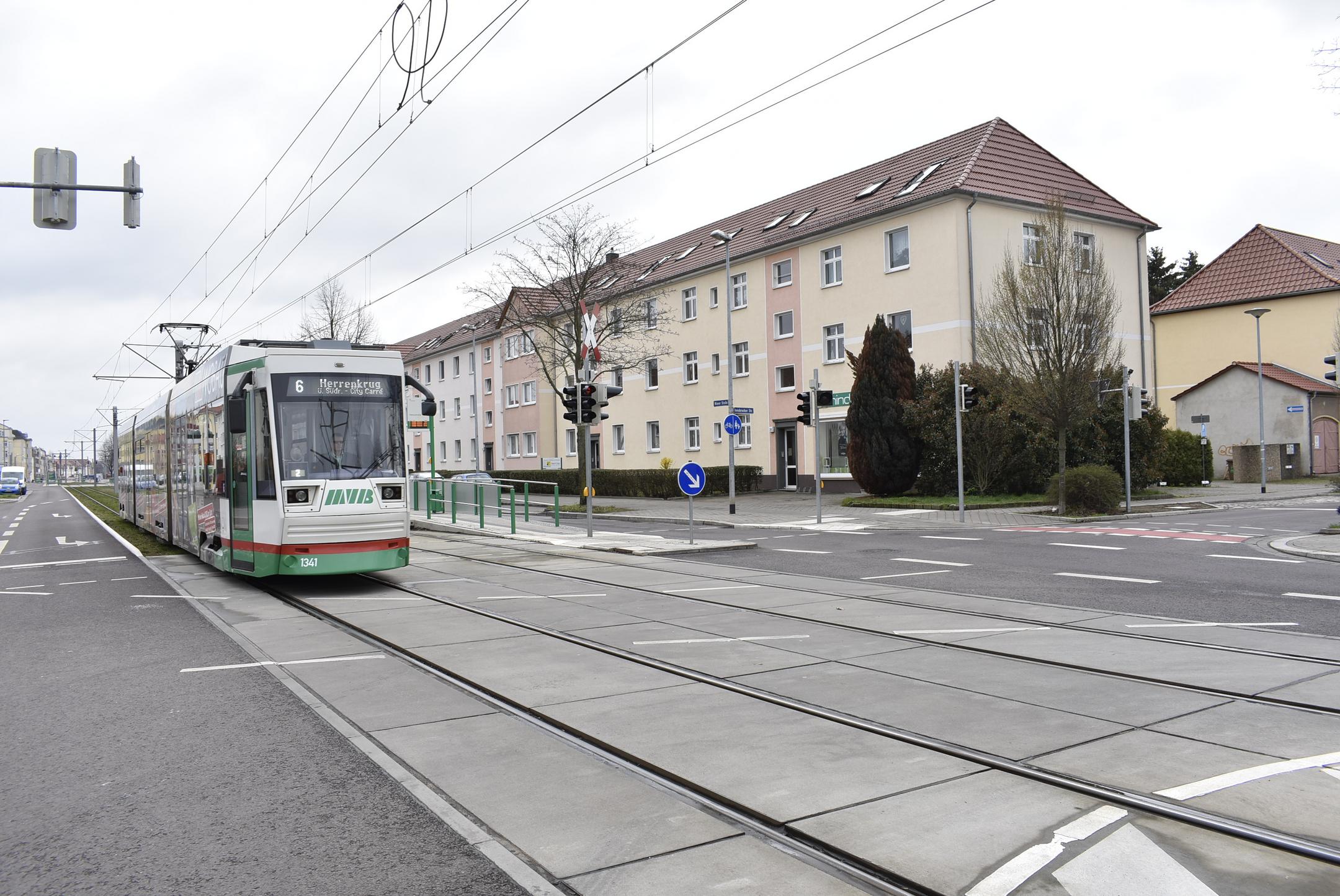 Die Magdeburger Straßenbahn fährt auf einer Kreuzung durch ein Wohngebiet.