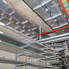 Kabelrinnen mit orangefarbenen Kabeln befestigt an Betondecke und Betonwand in einem Technikraum