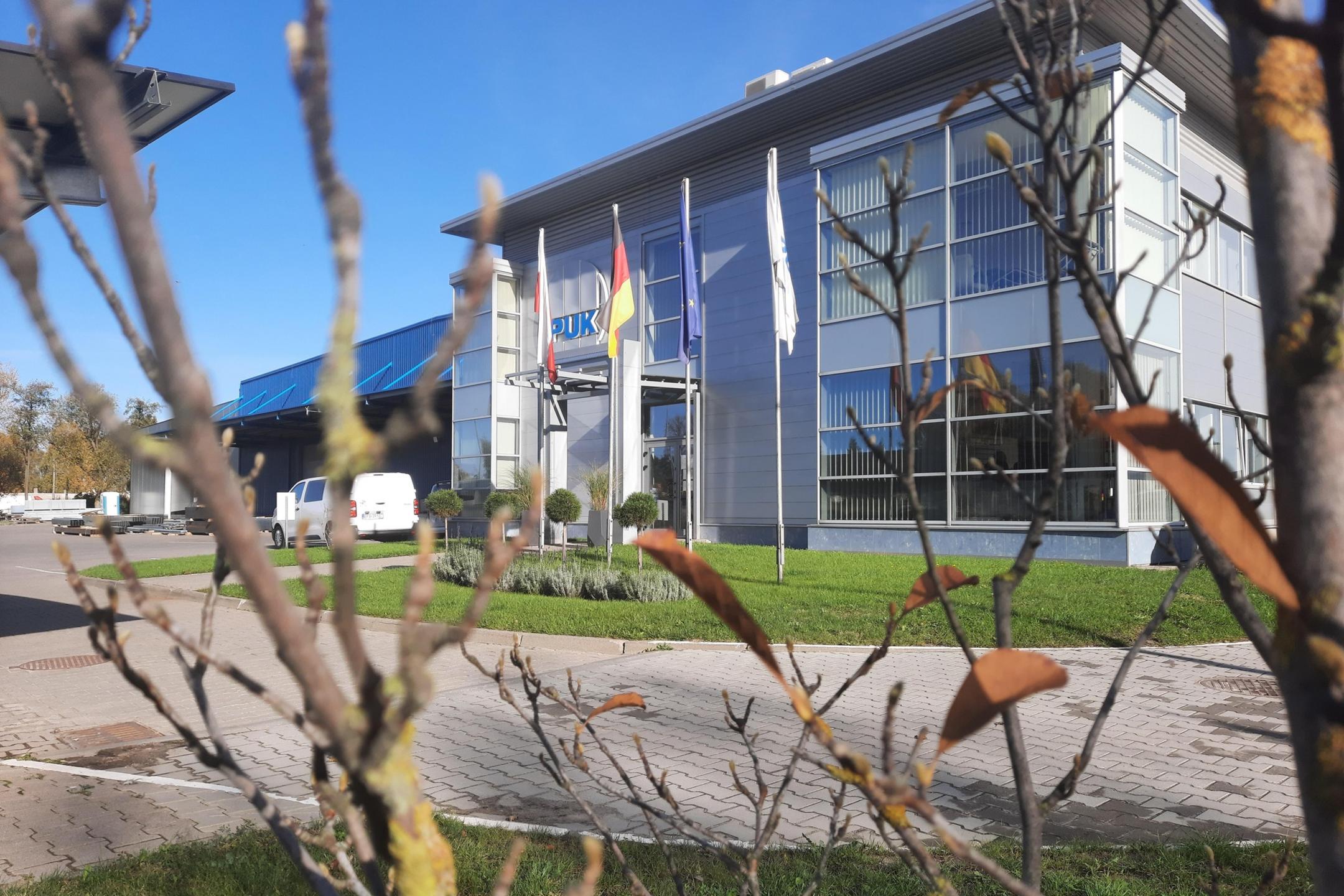EL-PUK company building in Lodz, Poland, with flags and a modern glass facade, photographed on a sunny day.