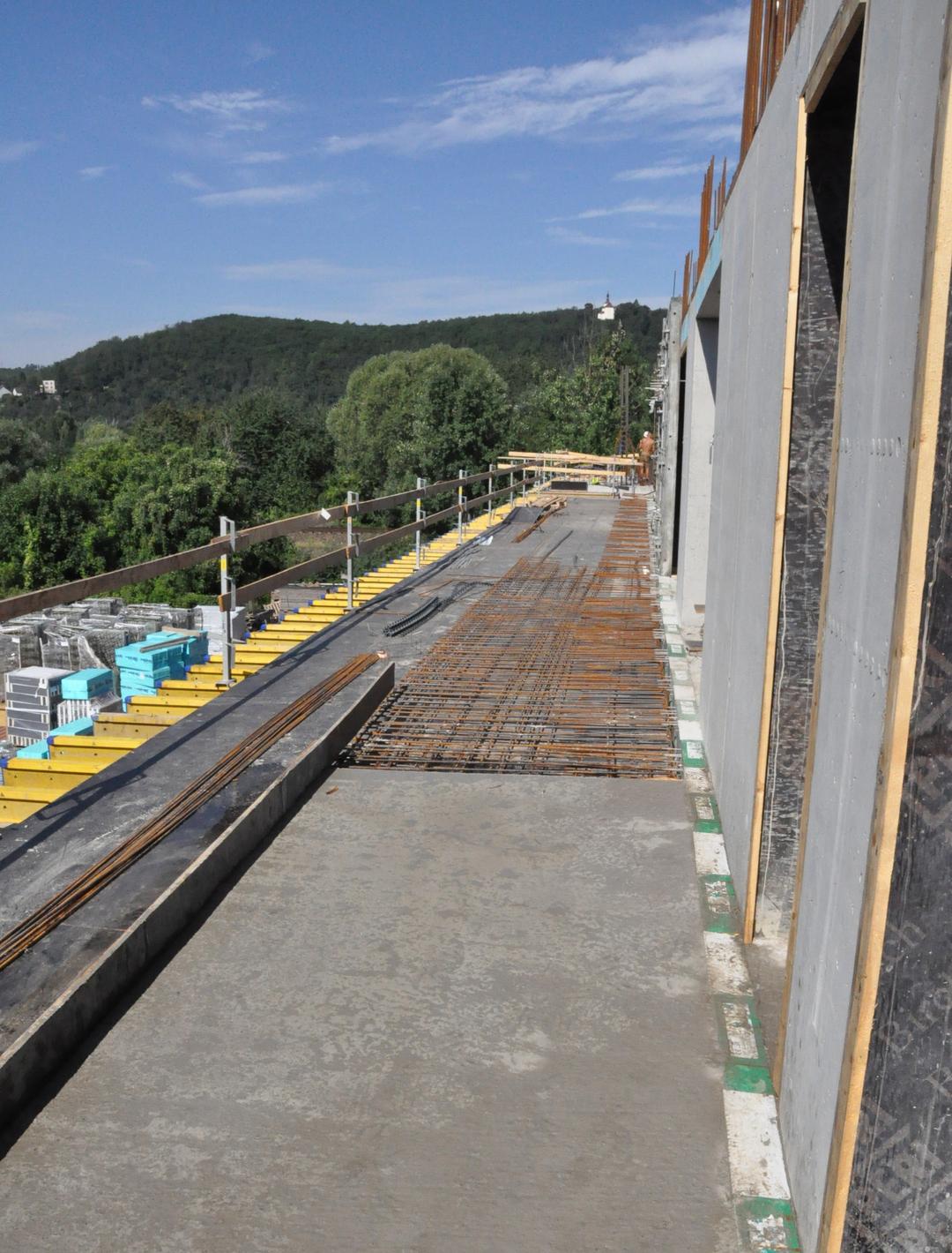 Blick auf die Baustelle bei sonnigem Wetter, im Hintergrund Wald.