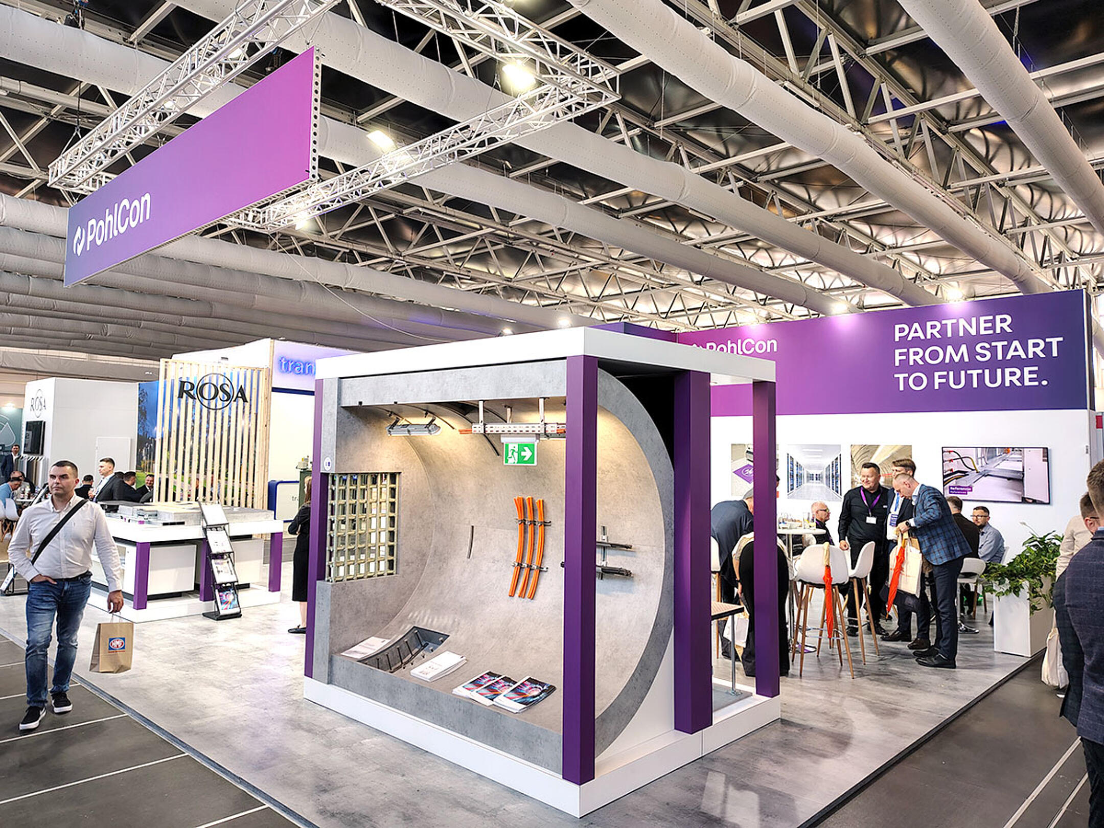 PohlCon-Messestand mit großem Tunnelmodell, ausgestellten Bauprodukten und Besuchern im Gespräch auf einer Fachmesse.