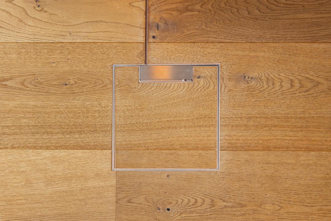 Blick auf ein geschlossenes Bodeninstallationssystem in einem Parkettboden.