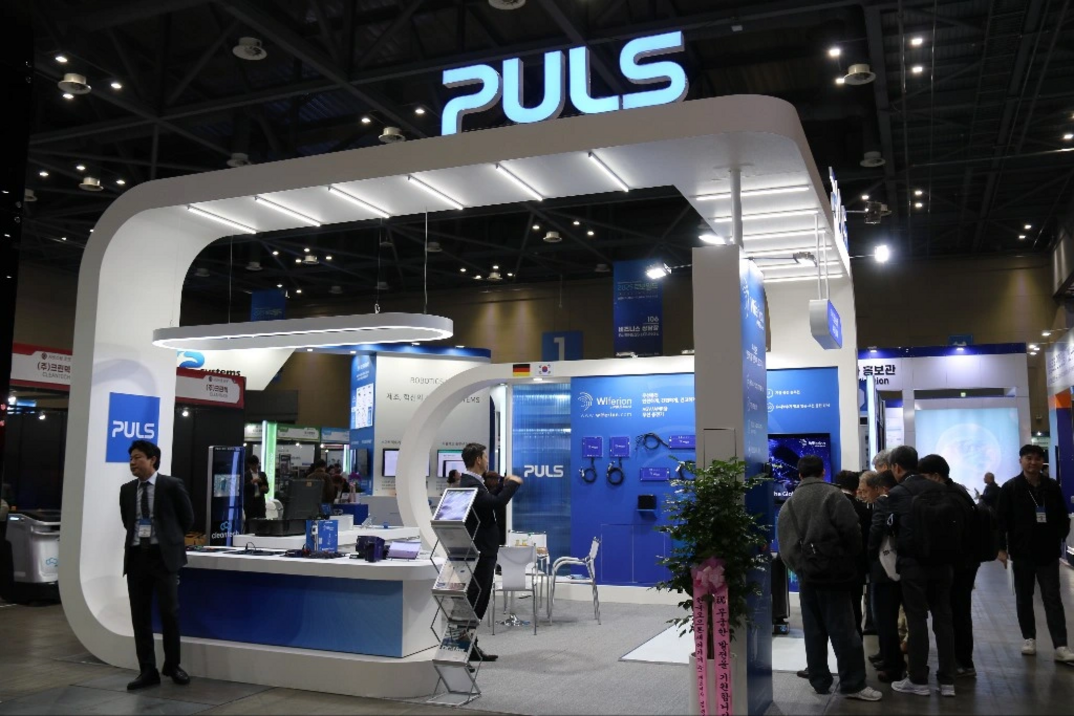 Ein Messestand von PULS mit Besuchern und Ausstellungsprodukten auf der Messe.