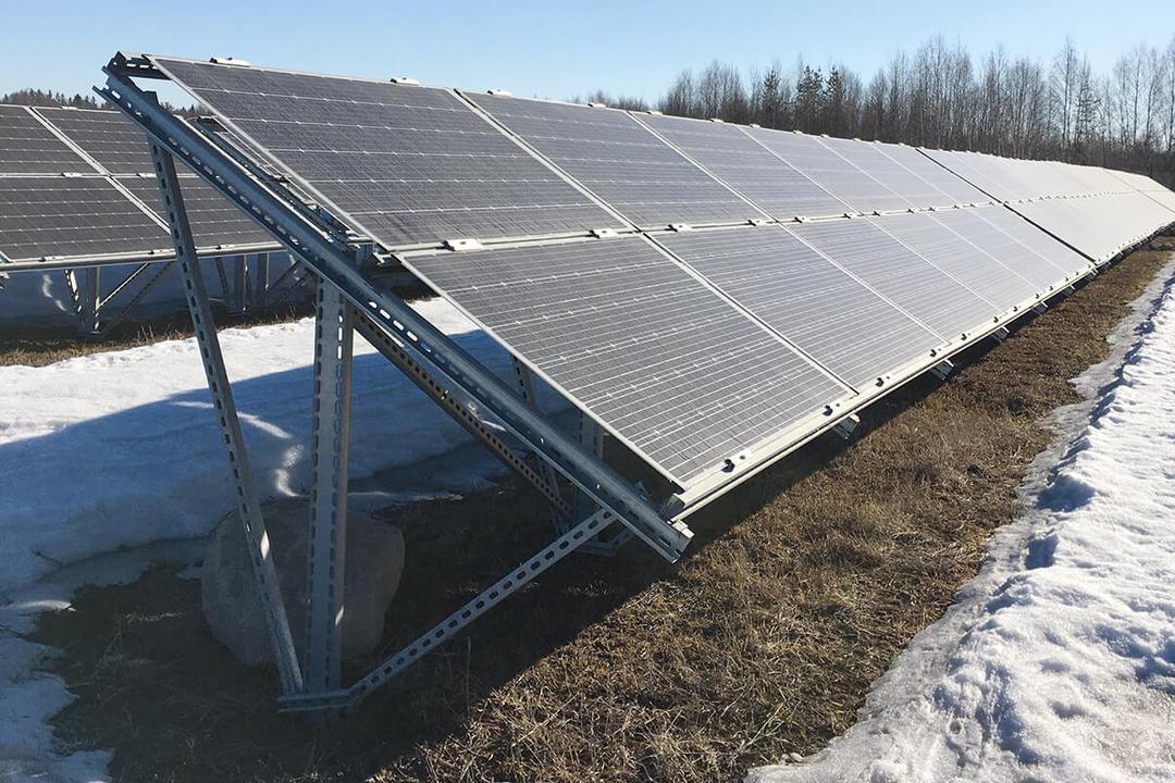 Schräg montierte Photovoltaikmodule auf verzinkter Stahlunterkonstruktion in verschneiter Landschaft bei klarem Winterwetter.