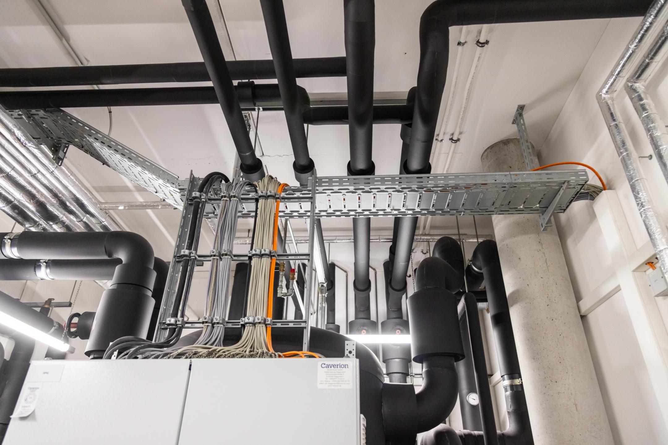 Verteilerkasten im Anschnitt mit anschließenden Kabelleitern und Kabelrinnen, die Kabel tragen.