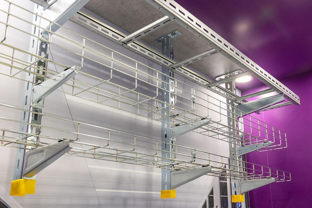 Installierte Gitter- und Kabelrinnen an einer Wand mit verzinkten Konsolen zur strukturierten Kabelführung im Rechenzentrum.