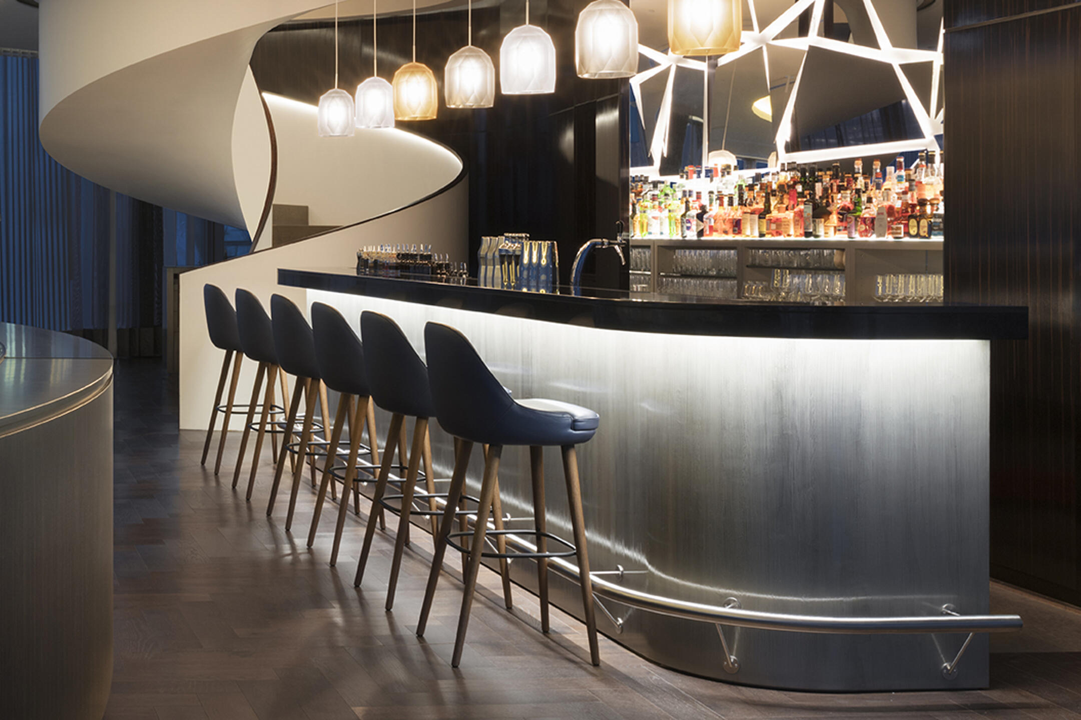Stylische Hotelbar mit moderner Beleuchtung, eleganter Theke und gemütlichen Sitzplätzen an hohen Barhockern.