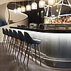 Stylische Hotelbar mit moderner Beleuchtung, eleganter Theke und gemütlichen Sitzplätzen an hohen Barhockern.