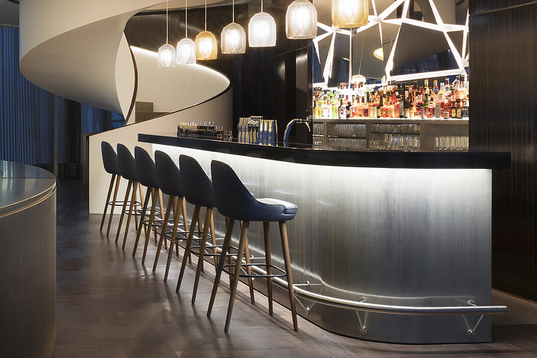 Stylische Hotelbar mit moderner Beleuchtung, eleganter Theke und gemütlichen Sitzplätzen an hohen Barhockern.