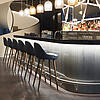 Stylische Hotelbar mit moderner Beleuchtung, eleganter Theke und gemütlichen Sitzplätzen an hohen Barhockern.