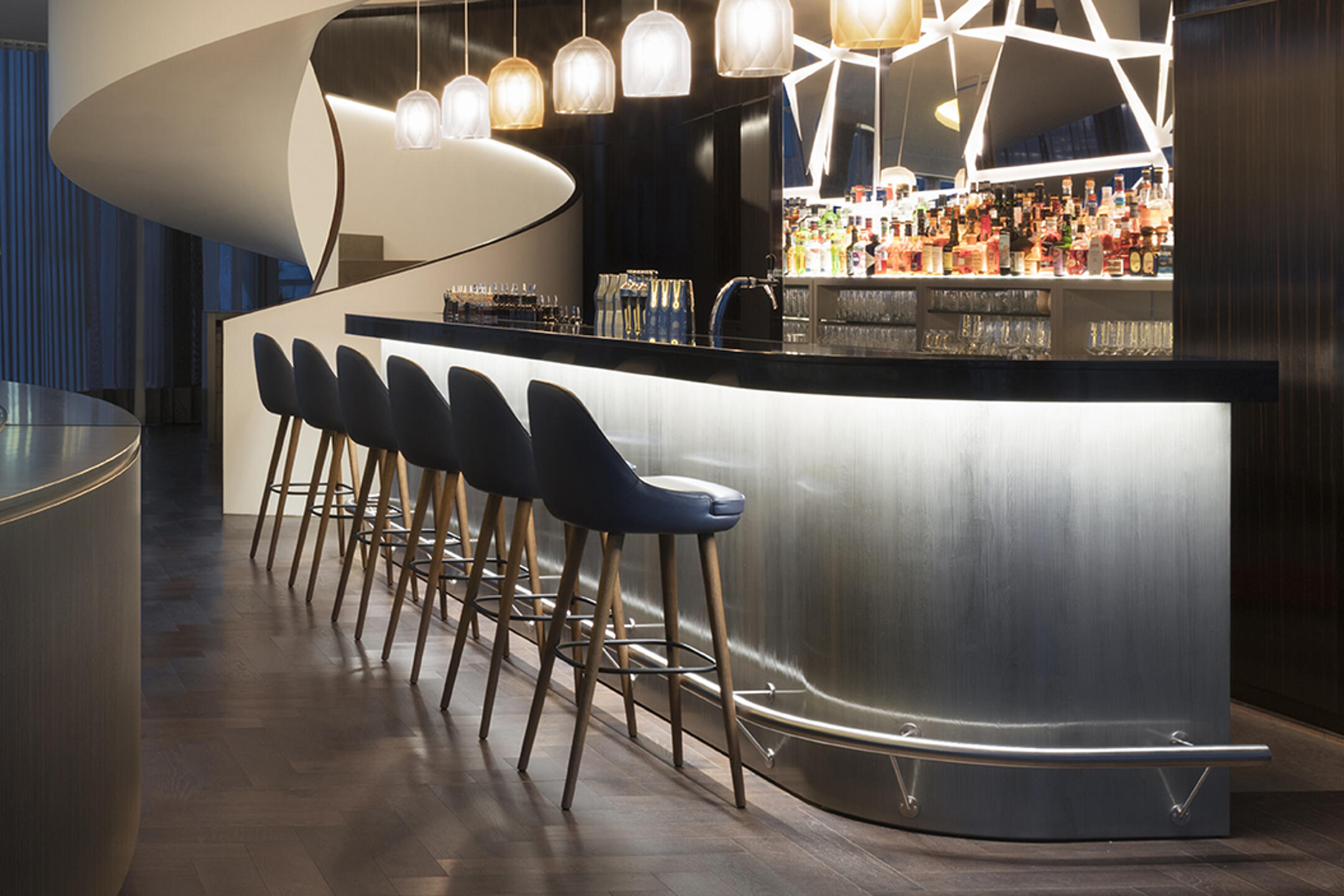 Stylische Hotelbar mit moderner Beleuchtung, eleganter Theke und gemütlichen Sitzplätzen an hohen Barhockern.