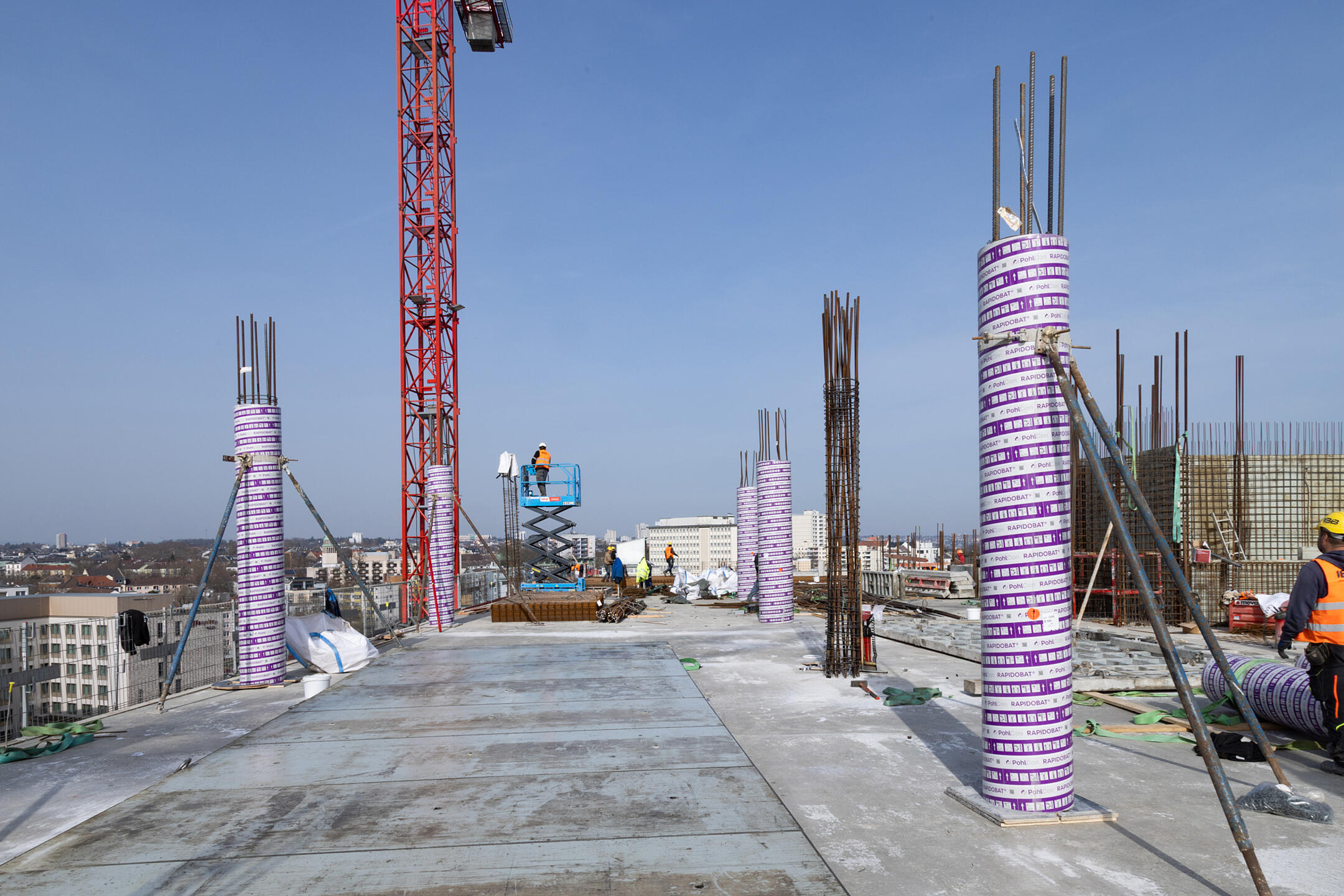 Baustelle während der Rohbauphase mit eingeschalten Betonstützen, blauer Himmel im Hintergrund
