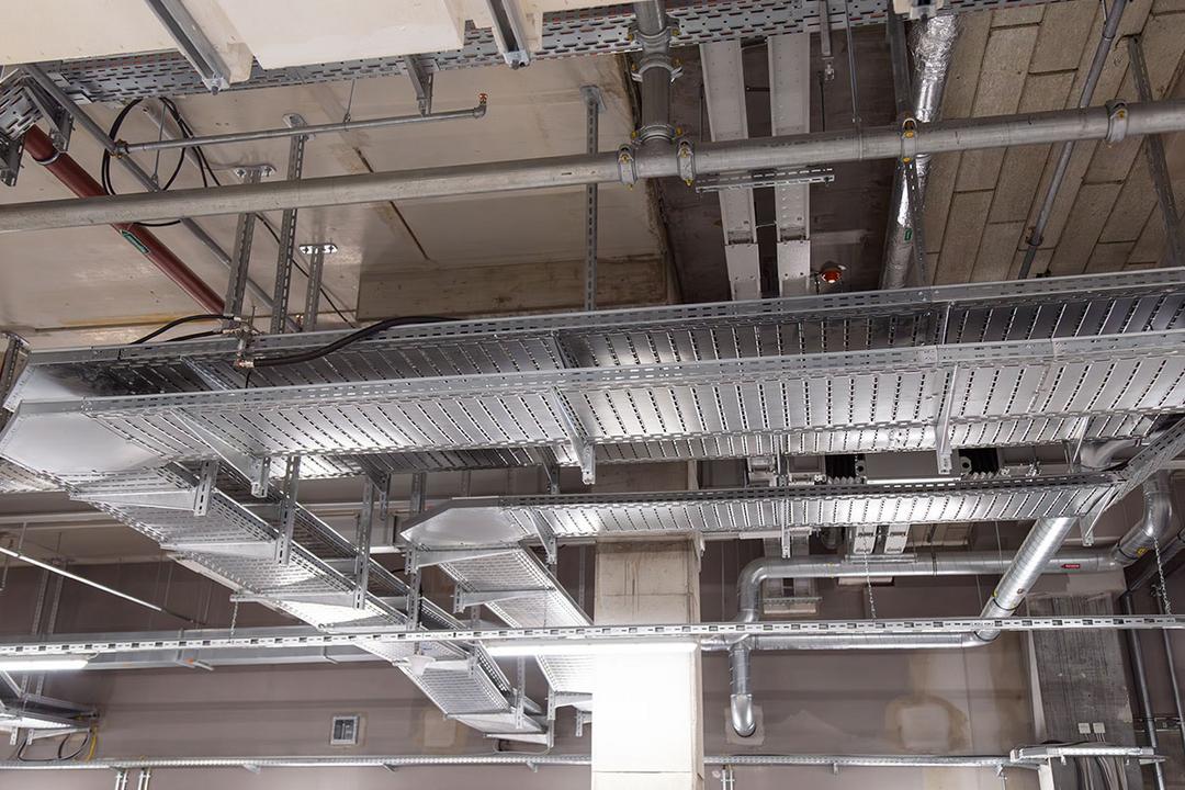 Industrielle Decke mit Kabelrinnen, Rohrleitungen und Betonstützen in modernem Innenraum