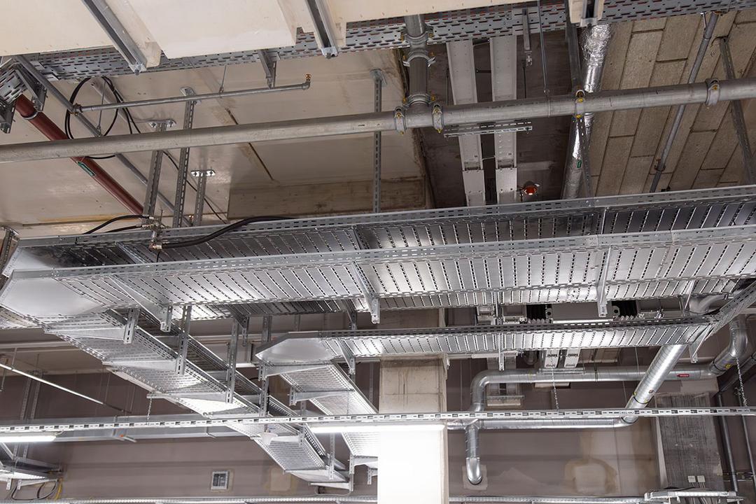 Industrielle Decke mit Kabelrinnen, Rohrleitungen und Betonstützen in modernem Innenraum