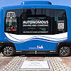 Ein autonomes Shuttle für den öffentlichen Personennahverkehr, das im Freien über einer kontaktlosen Ladestation parkt.
