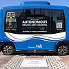 Ein autonomes Shuttle für den öffentlichen Personennahverkehr, das im Freien über einer kontaktlosen Ladestation parkt.