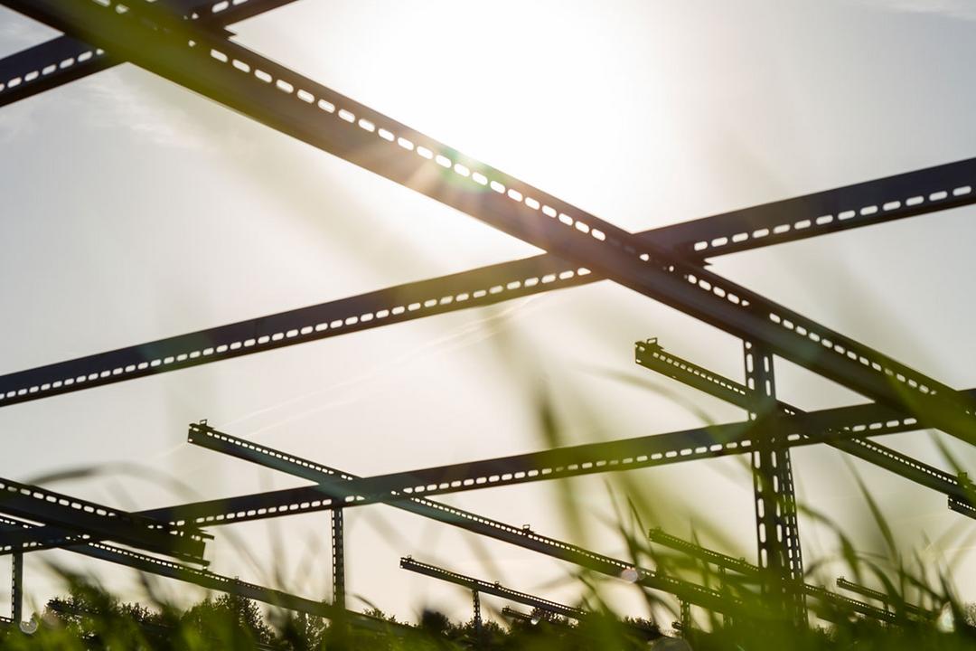 Unterkonstruktionen für Solarpanele aufgenommen aus der Froschperspektive mit Blick in die Sonne und Gras am unteren Bildrand