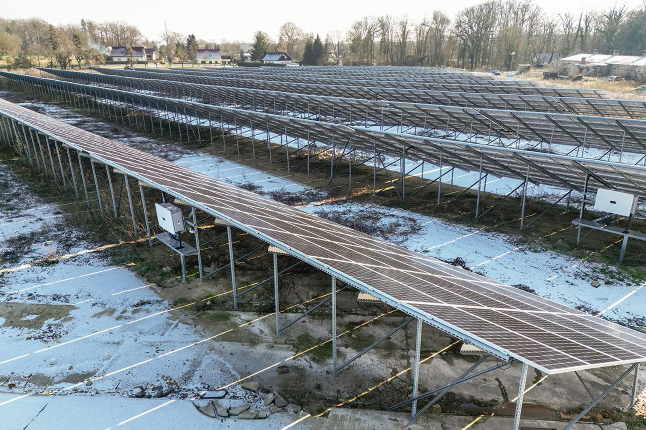 Rückansicht auf die Solarpanele mit erkennbaren Stützen, teilweise schneebedeckter Boden