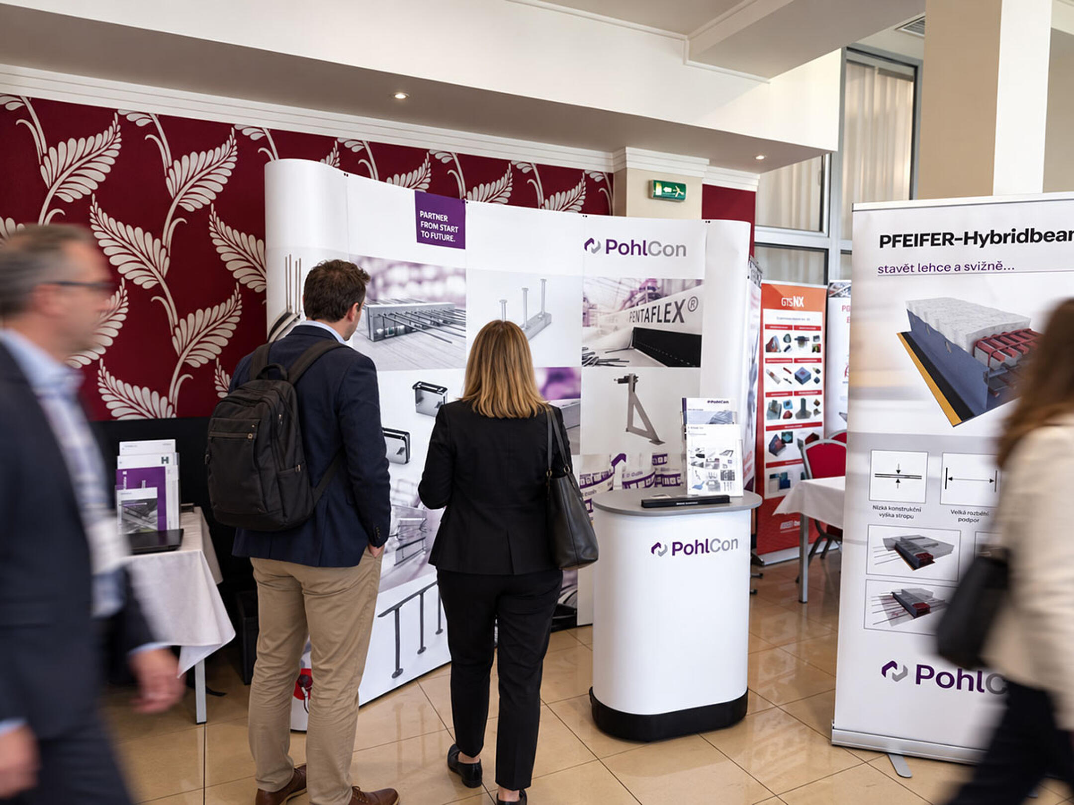 Besucher informieren sich am PohlCon-Messestand über Bauprodukte und Befestigungslösungen auf einer Fachkonferenz.